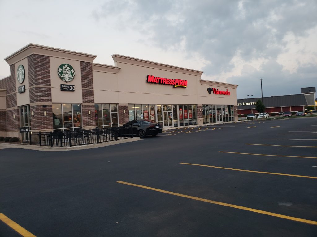 A sealcoating job done in Bradley, IL showing a Starbucks and Mattress Firm business.
